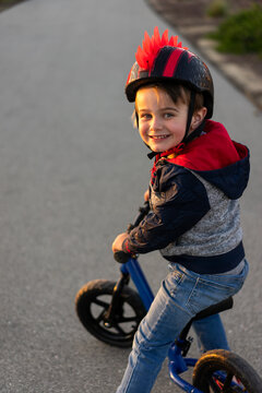 Happy young boy on a balance bike smiling at the camera