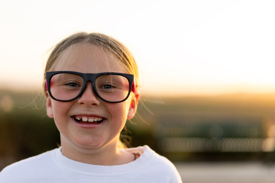 Young girl with blond hair smiling at the camera at a park
