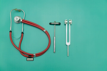 red stethoscope, tuning fork and medical hammer on green Background, Space for Text, Space for Logo