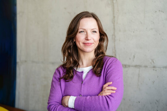 Confident businesswoman smiling in purple sweater at office