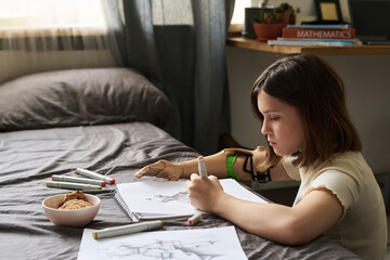 Child with prosthesis sketching on paper in cozy bedroom setting