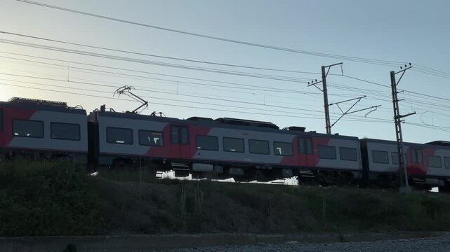 Russia, Sochi, 08/28/2025. An electric train travels along a railway at sunset. An electric train moves through the south to the sea. Summer day.