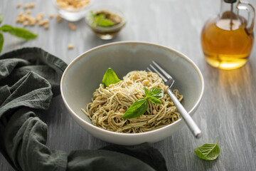 Spaghetti with pesto sauce and  cheese in plate on the table.