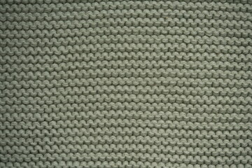 green texture of knitted wool fabric as a background, green smooth symmetrical lines of hand-knitted needlework pattern	
