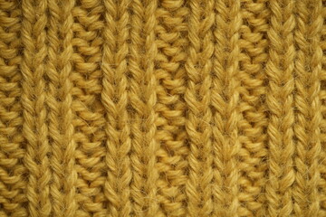 mustard yellow texture of knitted wool fabric as a background, smooth vertical lines of hand-knitted ribbed pattern in warm wool yarn