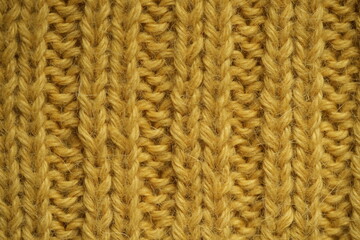 mustard yellow texture of knitted wool fabric as a background, smooth vertical lines of hand-knitted ribbed pattern in warm wool yarn