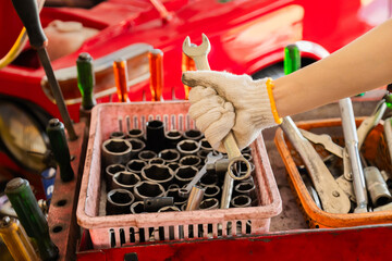 Small business garage mechanics in small business garage grips tools with safety glove, close-up wrench fix  preparation, workshop focus, professional readiness in automotive repair work by technician