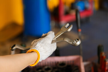 Obraz premium Small business garage mechanics in small business garage grips tools with safety glove, close-up wrench fix preparation, workshop focus, professional readiness in automotive repair work by technician