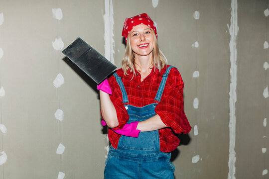 Confident DIY worker plastering drywall indoors with a smile