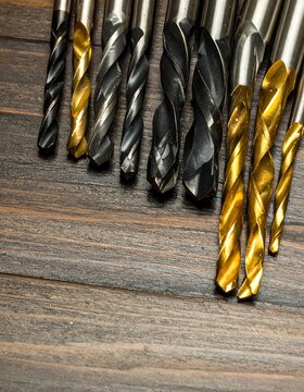 Various drill bits on a dark wooden surface