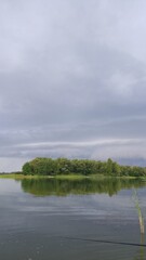 big clouds before thunderstorm over blue river, greenery along river