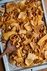 Various snacks baked on a tray with wooden spoons on a wooden table.