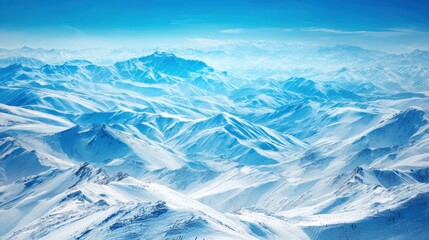 Snowy Mountainscape: An expansive aerial view showcases a range of snow-covered peaks, bathed in the crisp light of a clear, blue sky, a testament to nature's raw and untamed beauty.