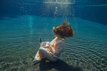 Businesswoman working underwater with laptop in swimming pool