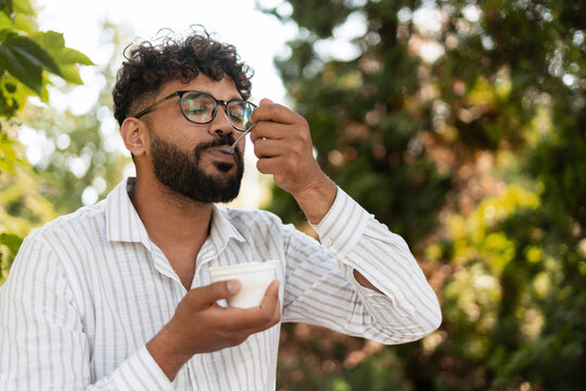 Young man enjoying a tasty dessert outdoors in a park