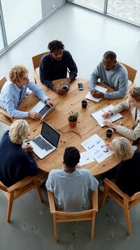 A diverse business team collaborates during a meeting around a round table in a modern office, a top view concept of teamwork, corporate strategy, and inclusive workplace culture
