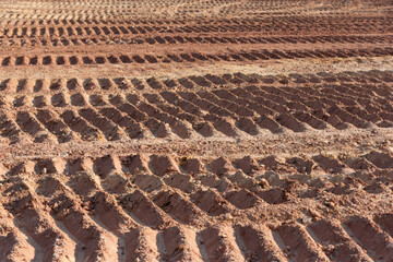 Background image showing tracks left by a tracked engineering vehicle on a dirt road surface