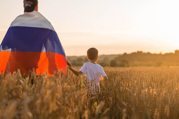 Patriotism. A father and son with the Russian flag in a wheat field at sunset. A family with a flag...