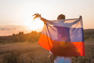 Patriotism. A father and son with the Russian flag in a wheat field at sunset. A family with a flag...