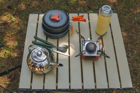 Cooking set and utensils for travelling or camping on top of a picnic table.