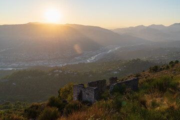 Epic golden hour view from the mountains above Nice, France, with ancient ruins overlooking the stunning Var river valley at sunset.