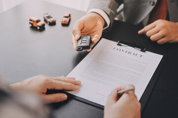 Car salesman gave the keys to the customers who signed the purchase contract legally, Successful completion of car sales, Purchase contract and key delivery.