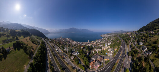 Sun shining over Montreux along the Lake of Geneva in Switzerland with the French and Swiss Alps in the background and A9 freeway in the foreground