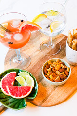 Gin and tonic and grapefruit juice cocktails, with wodka grapeftuir and lime, snacks on table, nuts, breadsticks, drinking cocktails with friends