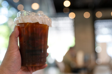 Holding plastic cups of delicious iced americano coffee