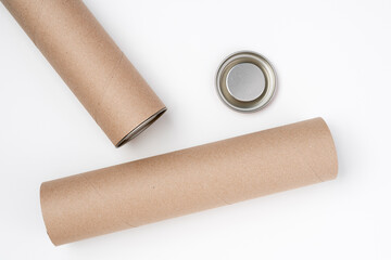 Two opened cardboard tubes with metal lids lying on white background