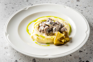 Mashed potatoes with creamy mushroom sauce, green herb oil drizzle, and pickled vegetables on a white plate. Gourmet presentation, ideal for food photography and culinary content.