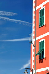 Vermilion and white facade standing out against a blue sky with contrails of a house on Via San Giacomo Street. Riomaggiore-Cinque Terre NP-Italy-221