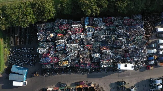 Aerial view of a junkyard filled with crushed cars, containers, and other metal debris, reflecting a somber industrial landscape, Ghent, Flanders, Belgium.
