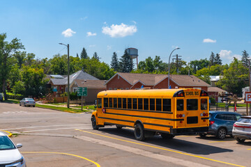 School bus leaving intersection in sunny small town © unai