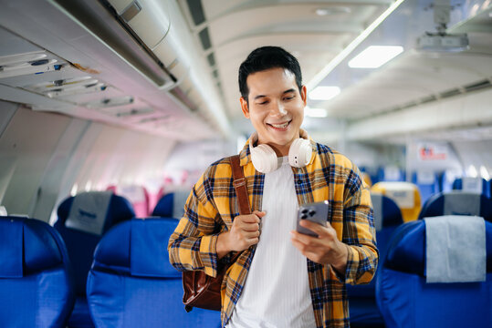 Smiling young traveler with headphones and backpack using a smartphone while boarding a plane. Perfect for travel, lifestyle, adventure, and modern digital nomad concepts.