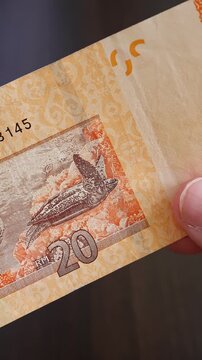 Vertical macro shot of man's hands and malaysian ringgit (MYR) banknotes. Concept of saving money for retirement, cash settlement, financial success, literacy and income planning in Malaysia.