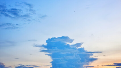 A striking, solitary cumulus cloud formation against a soft, gradient sky of blue, pink, and orange at dusk. , symbolizing solitude and majesty