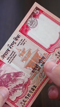 Vertical macro shot of man's hands and nepalese rupee (NPR) banknotes. Concept of saving money for retirement, cash settlement, financial success, literacy and income planning in Nepal. Close up view.