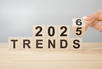 Hand flipping wooden block to change year from 2025 to 2026 over TRENDS word for new business concepts ahead