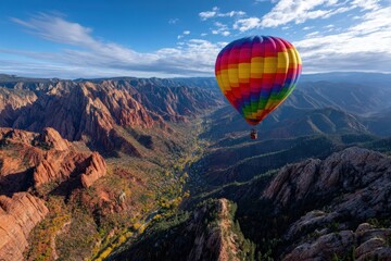 Fototapeta premium Colorful hot air balloon floats over striking canyon landscape at sunrise