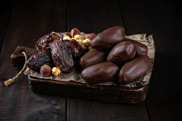 Date in chocolate glaze on craft paper and wooden boards. Healthy sweets, natural desserts, sugar free treats, clean eating concept.
