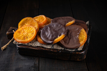 Orange in chocolate glaze on craft paper and wooden boards. Healthy sweets, natural desserts, sugar free treats, clean eating concept.