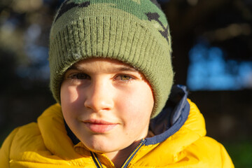 Portrait of smiling child wearing winter clothes outdoors in sunlight