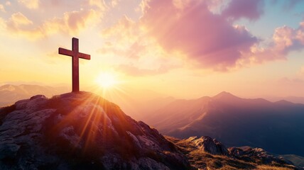 Obraz premium Beautiful sunset over mountains with a cross on a rocky hilltop creating a serene atmosphere
