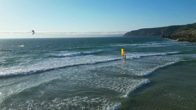 Flying along the sea following a windsurfer riding waves at guincho beach,Guincho beach It is very windy and offers excellent conditions for surfing, kitesurfing and windsurfing.Cascais,Portugal.