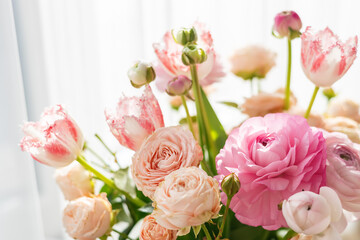 Close-up fresh peach and pink ranunculus blooms basking in gentle natural light, evoking love and grace for floral art