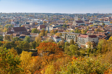 Obraz premium Autumn view over Vilnius showcasing colorful foliage and historic architecture on a sunny day