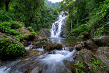 Fototapeta premium Majestic waterfall cascading into a serene pool surrounded by lush greenery