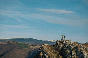 Hikers celebrating reaching mountain top with trekking poles