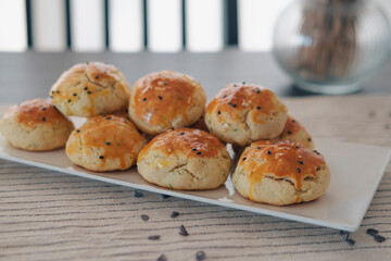 turkish savory pastry pogaca with dill and black sesame or cumin, homemade quick snack served on darck table and table cloth